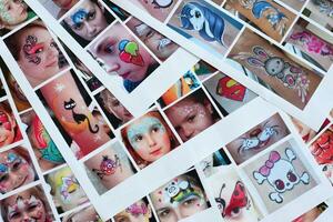 Many catalog pages with printed kids portraits with colorful face painting photo