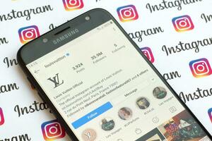 Louis Vuitton official instagram account on smartphone screen on paper instagram banner. photo