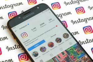 Main official instagram account on smartphone screen on paper instagram banner. photo