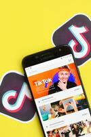 Tiktok application on samsung smartphone screen on yellow background. TikTok is a popular video-sharing social networking service owned by ByteDance photo