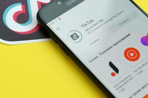 Tiktok application in playmarket on samsung smartphone screen on yellow background. TikTok is a popular video-sharing social networking service owned by ByteDance photo
