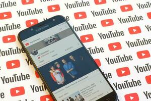 One Direction official youtube channel on smartphone screen on paper youtube background. photo