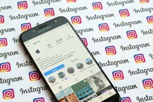 Apple official instagram account on smartphone screen on paper instagram banner. photo