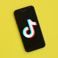 Tik Tok logo en Samsung teléfono inteligente pantalla en amarillo antecedentes. Tik Tok es un popular compartir videos social redes Servicio poseído por bytedance foto