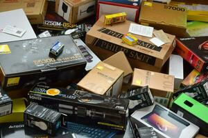 Big pile of many cardboard boxes from electronic products of famous manufacturers. Disposable wrappings of domestic use goods. Waste paper recycling photo