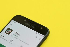 Tiktok application in playmarket on samsung smartphone screen on yellow background. TikTok is a popular video-sharing social networking service owned by ByteDance photo