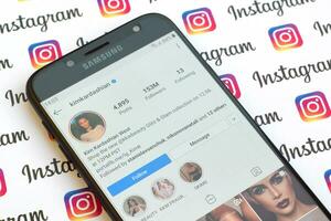 Kim Kardashian West official instagram account on smartphone screen on paper instagram banner. photo