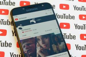 Ed Sheeran official youtube channel on smartphone screen on paper youtube background. photo