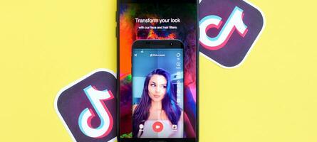Tiktok application on samsung smartphone screen on yellow background. TikTok is a popular video-sharing social networking service owned by ByteDance photo