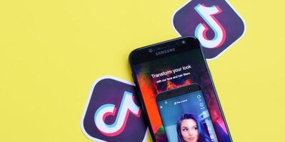 Tiktok application on samsung smartphone screen on yellow background. TikTok is a popular video-sharing social networking service owned by ByteDance photo