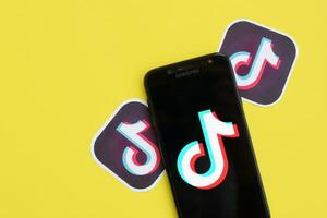 Tik Tok logo en Samsung teléfono inteligente pantalla en amarillo antecedentes. Tik Tok es un popular compartir videos social redes Servicio poseído por bytedance foto