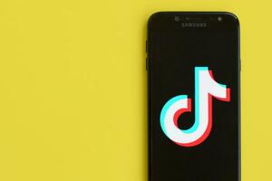 Tik Tok logo en Samsung teléfono inteligente pantalla en amarillo antecedentes. Tik Tok es un popular compartir videos social redes Servicio poseído por bytedance foto