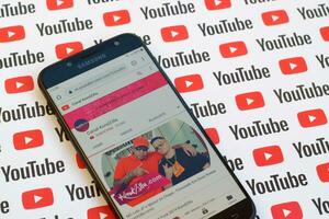 Canal KondZilla official youtube channel on smartphone screen on paper youtube background. photo
