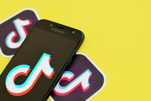 Tik Tok logo en Samsung teléfono inteligente pantalla en amarillo antecedentes. Tik Tok es un popular compartir videos social redes Servicio poseído por bytedance foto