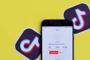 Tiktok application on samsung smartphone screen on yellow background. TikTok is a popular video-sharing social networking service owned by ByteDance photo