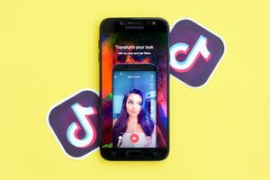 Tik Tok solicitud en Samsung teléfono inteligente pantalla en amarillo antecedentes. Tik Tok es un popular compartir videos social redes Servicio poseído por bytedance foto