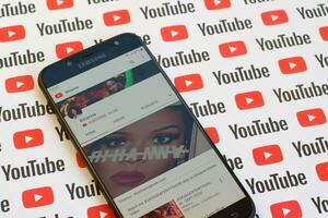 Rihanna official youtube channel on smartphone screen on paper youtube background. photo