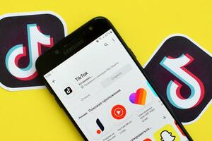 Tiktok application in playmarket on samsung smartphone screen on yellow background. TikTok is a popular video-sharing social networking service owned by ByteDance photo