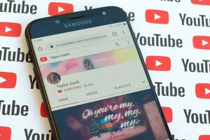 Taylor Swift official youtube channel on smartphone screen on paper youtube background. photo