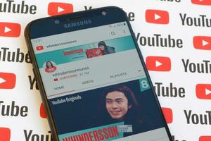 Whinderssonnunes official youtube channel on smartphone screen on paper youtube background. photo