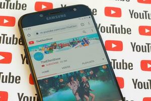 TheEllenShow official youtube channel on smartphone screen on paper youtube background. photo