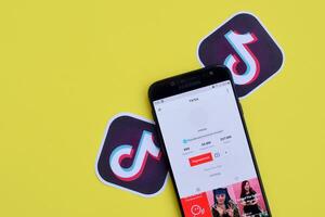 Tiktok application on samsung smartphone screen on yellow background. TikTok is a popular video-sharing social networking service owned by ByteDance photo