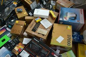 Big pile of many cardboard boxes from electronic products of famous manufacturers. Disposable wrappings of domestic use goods. Waste paper recycling photo