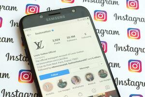 Louis Vuitton official instagram account on smartphone screen on paper instagram banner. photo