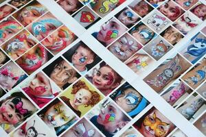 Many catalog pages with printed kids portraits with colorful face painting photo