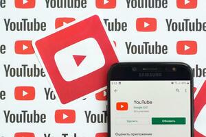 Youtube aplicación en Samsung teléfono inteligente pantalla en papel bandera con pequeño Youtube logos y inscripciones. Youtube es google subsidiario y americano más popular compartir videos plataforma foto