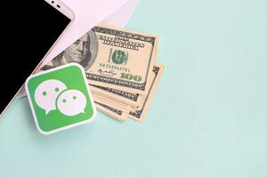 Wechat paper logo lies with envelope full of dollar bills and smartphone photo