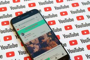 Justin Bieber official youtube channel on smartphone screen on paper youtube background. photo