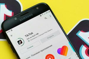 Tiktok application in playmarket on samsung smartphone screen on yellow background. TikTok is a popular video-sharing social networking service owned by ByteDance photo