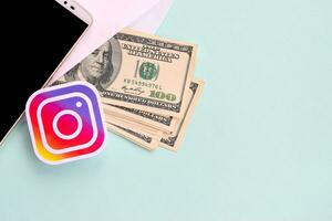 Instagram paper logo lies with envelope full of dollar bills and smartphone photo