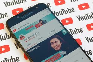 Whinderssonnunes official youtube channel on smartphone screen on paper youtube background. photo