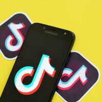 Tik Tok logo en Samsung teléfono inteligente pantalla en amarillo antecedentes. Tik Tok es un popular compartir videos social redes Servicio poseído por bytedance foto