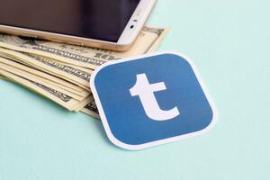 Tumblr paper logo lies with envelope full of dollar bills and smartphone photo