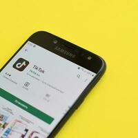 Tiktok application in playmarket on samsung smartphone screen on yellow background. TikTok is a popular video-sharing social networking service owned by ByteDance photo