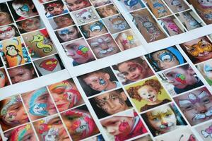 Many catalog pages with printed kids portraits with colorful face painting photo