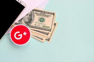 Google plus paper logo lies with envelope full of dollar bills and smartphone photo