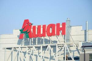 KHARKOV, UKRAINE - OCTOBER 20, 2019 Auchan supermarket logo on the building roof. Auchan is French international retail group photo