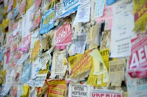 KHARKOV, UKRAINE - OCTOBER 2, 2019 Grunge Message Board with many advertisement. People spreading advertising and information on white paper than post it on metal fence photo