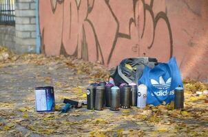 Jarkov, Ucrania - octubre 19, 2019 usado rociar latas para pintada pintura por muchos pintar marcas al aire libre en otoño hojas y pared pintura en fondo foto