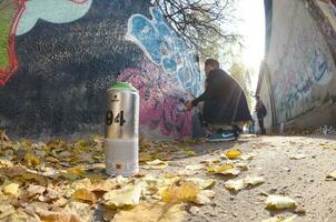 KHARKOV, UKRAINE - OCTOBER 19, 2019 Montana mtn 94 used spray can for graffiti painting outdoors in autumn leafs and artist in painting process photo