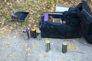 KHARKOV, UKRAINE - OCTOBER 19, 2019 Montana mtn 94 black hardcore dope and kobra used spray cans for graffiti painting outdoors in autumn leafs photo