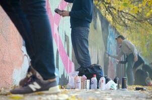 KHARKOV, UKRAINE - OCTOBER 19, 2019 Used spray cans for graffiti painting by many paint brands outdoors in autumn leafs and artist in painting process photo