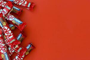 Kit Kat chocolate bars in red wrapping lies on yellow background is now produced globally by Nestle. Have a break - have a Kit Kat photo