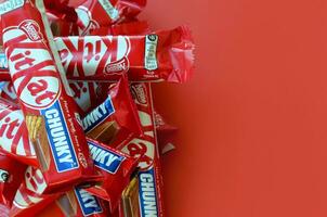 Kit Kat chocolate bars in red wrapping lies on yellow background is now produced globally by Nestle. Have a break - have a Kit Kat photo