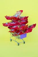 Kit Kat chocolate bars in small shopping cart on yellow background. Kit Kat is a famous brand of chocolates by Nestle company photo