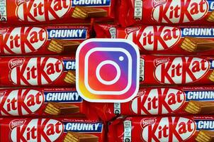 Instagram paper logo on many Kit Kat chocolate covered wafer bars in red wrapping. Advertising chocolate product in Instagram social network and world wide web photo